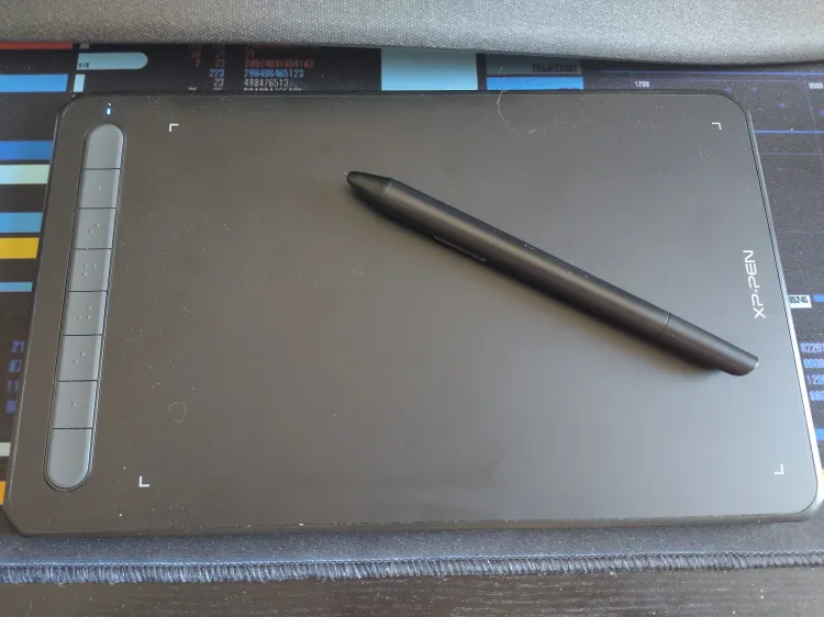 A wireless drawing pad with its pen on a desk with a Star Trek LCARS desk mat.